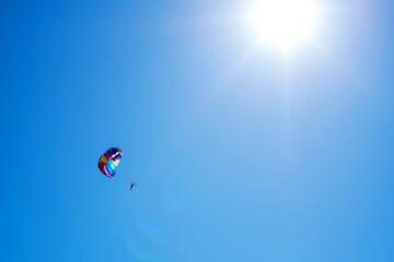 Tourists fly on a bright paraglider against the blue sky in the summer on a sunny day. Beach holidays, tourist marine entertainment. Parasailing