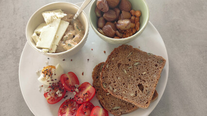 Frühstücksteller mit Brot, Tomate, Ei, Dip, Käse, Maronen und Nüssen