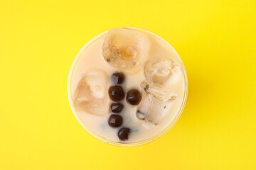 Tasty milk bubble tea in plastic cup on yellow background, top view