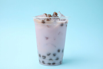 Tasty milk bubble tea in plastic cup on light blue background