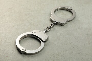 Classic chain handcuffs on grey table, closeup