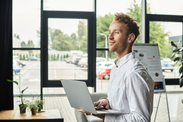 A professional with red hair works intently on a project, displaying focus in a bright office setting.