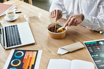 A focused professional indulges in lunch while multitasking on a project in a stylish office.