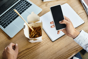 A diligent man in a white shirt reviews a project, taking a brief break with lunch by his side.