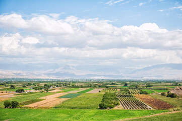 Naklejka premium Vast farmland stretches towards the distant mountains under a scenic sky