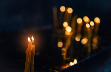Bokeh lights surround the burning candle, creating a peaceful and spiritual atmosphere