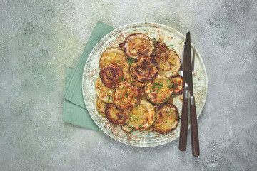 fried zucchini, cut into rings, with garlic and herbs, on a plate, top view, homemade, no people,