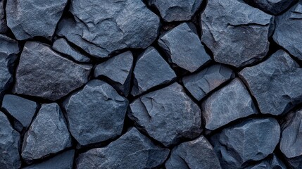 Dark cobblestone texture with rough, uneven black stones and cracks forming a natural, rugged pattern on a plain background 