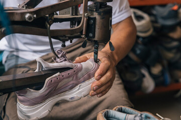 Shoe repair process in a workshop, a worker repairing the sole of a shoe on a sewing machine