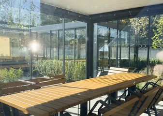 Fototapeta premium A spacious barbecue area with a canopy made from natural materials, enclosed. A patio with a table and chairs, sitting under a roofed structure.