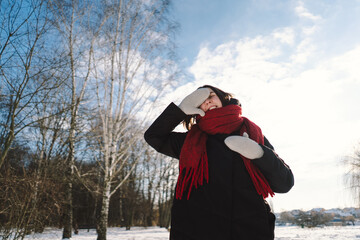 A smiling woman with a red scarf enjoys a snowy winter day in a serene forest setting beneath a...