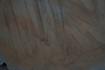 Sand artwork created on a surface with swirls and patterns, showcasing artistic design in natural...