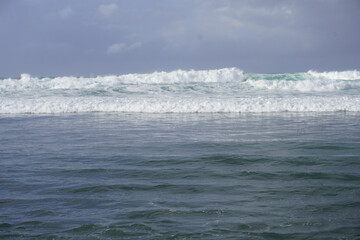 Ocean waves crashing on the shore, with calm water in the foreground