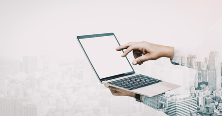 Double exposure image of businessman using computer on abstract modern city background. Future business and communication technology concept. Surreal futuristic multiple exposure interface. uds