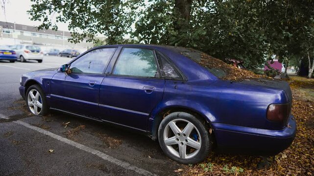 Car with dirty windows and flat tires, dry leaves fall autumn bird droppings dirt. Long standing parking car Abandoned vehicles in city after eviction or confiscation