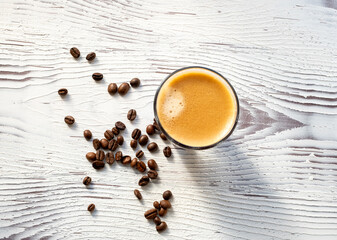 Coffee beans and espresso in a glass on a white wooden background