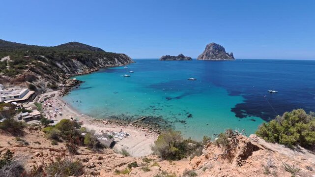Panoramic view of the famous Cala Hort beach on Ibiza with Es Vedra island in the background Clear turquoise waters of the Mediterranean with boats and sunbathers