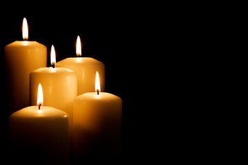 Burning white candles on a black background. Front view.