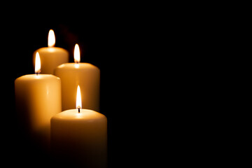 Burning white candles on a black background. Front view.