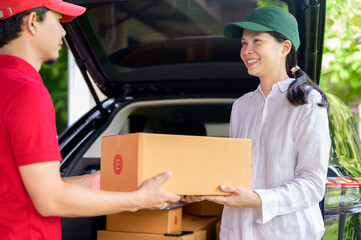 A delivery man in uniform and red hat delivering a parcel to a satisfied female Asian customer and friendly staff at a customer's home