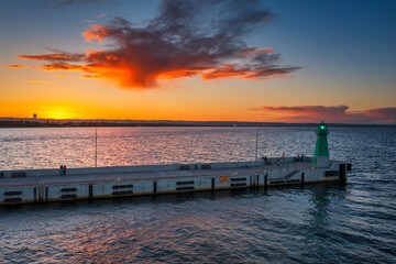 Obraz premium Green lighthouse on the western breakwater in Nowy Port at sunset, Gdansk.