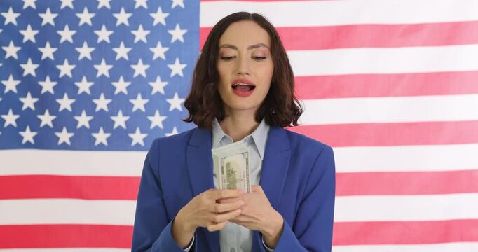 Confident woman in blue suit counts money against American flag. Businesswoman radiates success and ambition in politics and finance