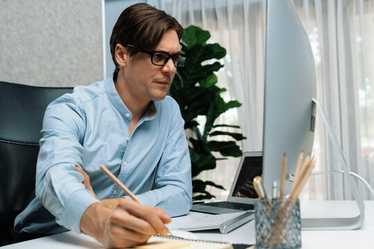 Stressful IT developer analyzing online software development information on pc and laptop with coding program on trial application project. Technical engineer writing crucial memo lists. Pecuniary.