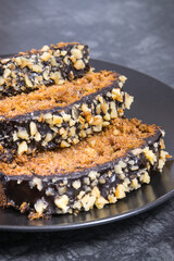 Pieces of zucchini dough with nuts and raisins on black plate