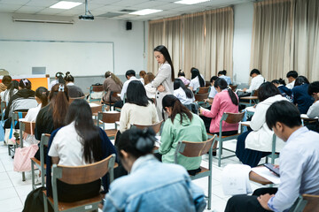 Obraz premium A teacher carefully monitors students taking an exam in a classroom, ensuring focus and discipline during academic assessment.
