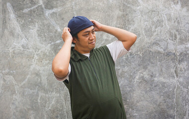 Man Adjusting His Hat Against a Textured Wall