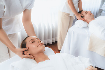 Obraz premium Caucasian couple enjoying relaxing anti-stress head massage and pampering facial beauty skin recreation leisure in dayspa modern light ambient at luxury resort or hotel spa salon. Quiescent