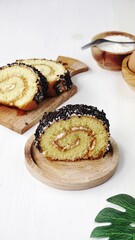 Slice of sponge cake with cream and messes chocolate on the top, ot called bolu gulung coklat serving on wooden plate. It usually eat for breakfast
