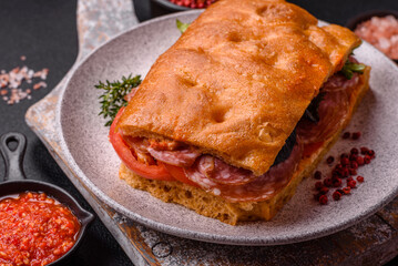 Focaccia with salami, cheese, tomatoes, arugula, salt, spices and herbs