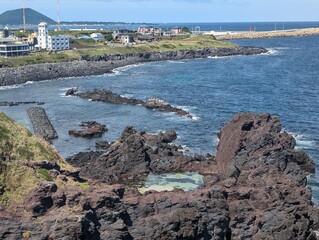 A scenic view of a rugged shoreline with a distant lighthouse