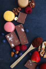 Macarons, chocolate, cookies, berries and various nuts on dark blue background. Top view.