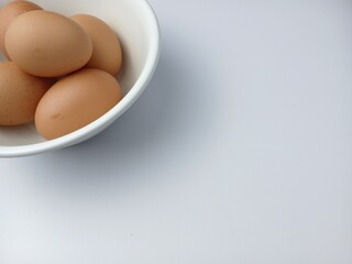Group of brown raw eggs on a bowl, with copy space for text  isolated on white background