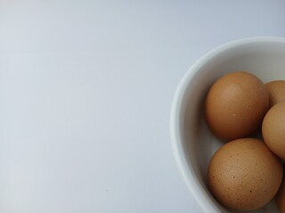 Group of brown raw eggs on a bowl, with copy space for text  isolated on white background