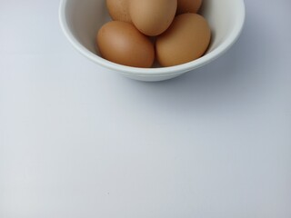 Group of brown raw eggs on a bowl, with copy space for text  isolated on white background
