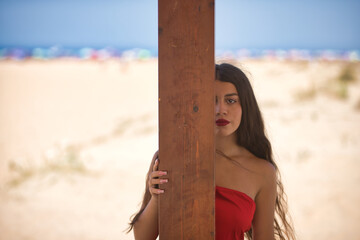 Young, beautiful, brunette woman with long hair, wearing a red dress, shy and reserved, hiding...