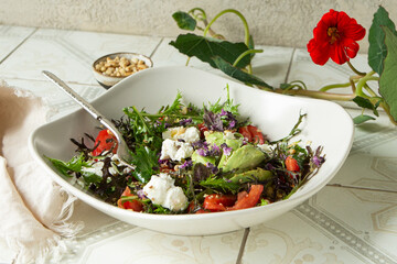 bowl of salad with avocado, ricotta and tomatoes on a light table