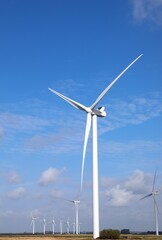 Fototapeta premium wind turbine with three blades rotating using wind power to produce electricity with zero environmental impact anc blue sky