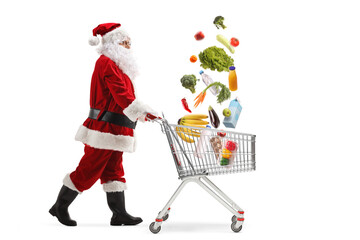 Full length profile shot of Santa Claus walking with a shopping cart and falling groceries
