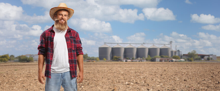 Farmer with a straw hat standing near tower sillos