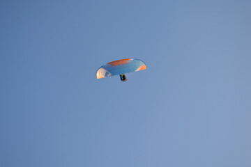 Paraglider flight against the background of a cloudless sky.