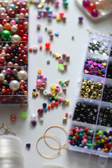Colorful beads, letter beads, threads and other jewelry making supplies on white background. Making friendship bracelets concept. Selective focus.
