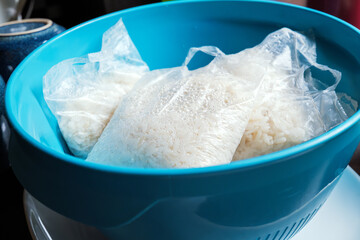 Cooked rice in a bag placed in a blue colander