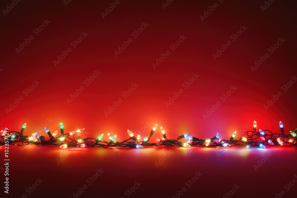 Poster string of colorful christmas lights is lying on a red background