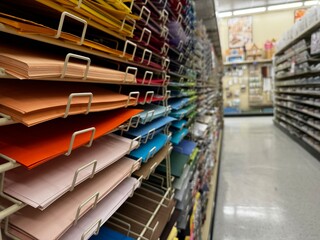 multi-colored paper sheets stacked on shelves in a craft store aisle