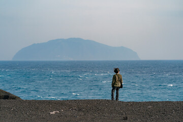 三宅島のスコリアの大地から海の景色を眺める子供