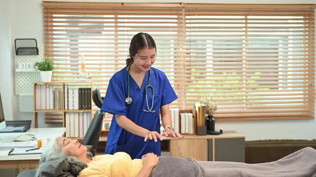 Female practitioner giving Reiki healing treatment to senior patient. Alternative medicine concept